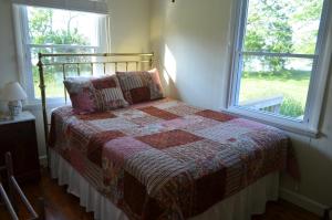 a bedroom with a bed with a quilt and a window at The Cottage at Heron Cove in Cambridge