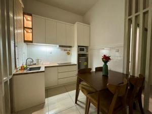 a kitchen with a table and chairs and a kitchen with white cabinets at Manhattan Suites ITCC by KinabaluKomfortHomestay - Iverie in Penampang