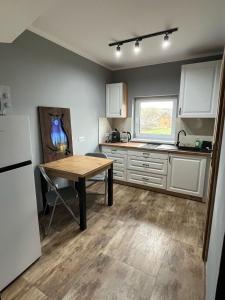 a kitchen with a wooden table and a refrigerator at Domki w Bieszczadach Kuźmina in Kuźmina