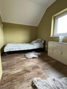 a bedroom with two beds and a window and wooden floors at Domki w Bieszczadach Kuźmina in Kuźmina