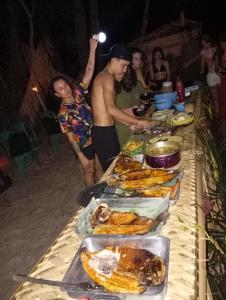 a table full of food with people standing around it at Redário Pô do Sol in Água Boa