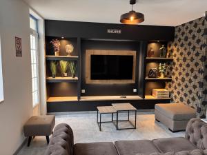 a living room with a couch and a flat screen tv at Le tilou in Fontenay-le-Pesnel