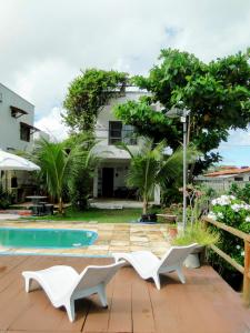 a patio with white chairs next to a pool at MaréVila Taíba - Casa de Praia com Wi-fi e Vista para o mar in Taíba