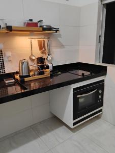 a kitchen with a black and white counter top at Quarto com Varanda - Recanto do Sabiá in Campinas