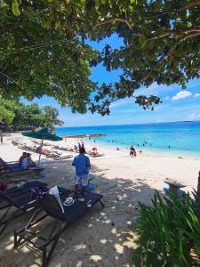 a person standing on a beach with people in the water at Mactan Newtown 2 Bedrooms Suite in Lapu Lapu City