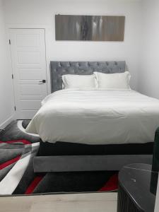 a bedroom with a large bed with white sheets at Carrington Cozy Suite, Calgary in YYC