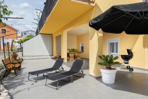 a patio with chairs and an umbrella on a building at Apartment Miha in Loborika +6 photos
