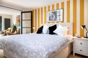 ein Schlafzimmer mit einem großen Bett mit gelben und weißen Streifen in der Unterkunft Waterfront Cottage - Apple Pie Luxury Escapes in Calstock
