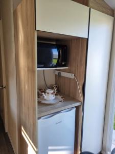 a small kitchen with a microwave and a cupboard at fantasy island in Ingoldmells