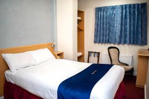 a bedroom with a bed and a chair and a window at Royal Square Hotel - NEC & Birmingham Airport in Marston Green