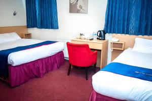 a room with two beds and a desk with a red chair at Royal Square Hotel - NEC & Birmingham Airport in Marston Green