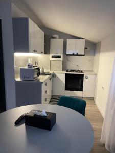 a kitchen with white cabinets and a table in a room at Happy apartment 2 in Chiajna
