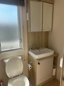 a bathroom with a toilet and a sink and a window at 18 Bay View in Wyke Regis +13 photos