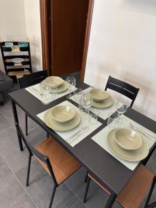 a black table with plates and wine glasses on it at Giulia's Apartment in Altavilla Milicia +16 photos
