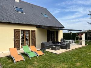a patio with chairs and a couch and a table at Villa Rose in Graignes