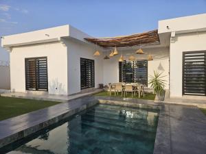 a villa with a swimming pool in front of a house at Villa Nossa in Keur Goonde