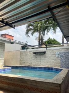 a swimming pool in a building with a palm tree at Casa com Piscina individual in Paulista