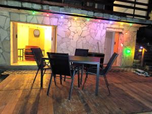 a table and chairs on a deck with a stone wall at Nyugalom Kulcsa in Kulcs