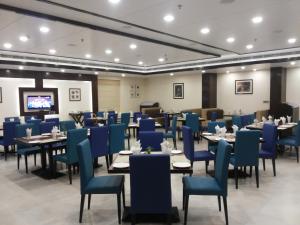 a dining room with blue chairs and tables at The Legend in Allahābād