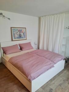 a bedroom with a large bed with pink sheets at Ferienwohnung Körnernest in Ettringen +2 photos