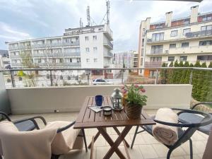 a table and chairs on a balcony with a view of a building at Wave and Sun Apartment in Hel