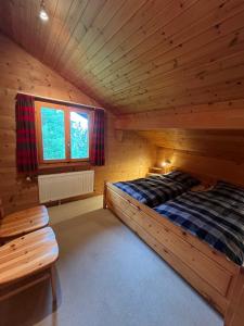 a log cabin bedroom with a bed and a window at Chalet Karin in Sankt Niklaus