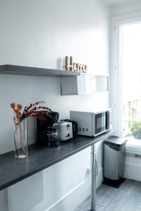 a kitchen with a counter with a microwave and a window at T2 à 3mn du métro Mairie de Montrouge in Montrouge +10 photos