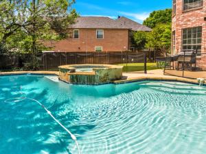 a swimming pool with a hose in front of a house at Heated Pool PoolTable HotTub Sleeps 16 Renovated in McKinney