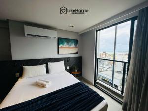 a bedroom with a bed and a large window at Edifício Way Tambaú in Tambaú