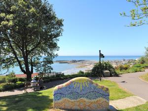 a bench in a park with a view of the ocean at Rona Cottage in Lyme Regis