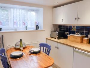 eine Küche mit einem Holztisch und einer Flasche Wein in der Unterkunft High Bullen Cottage in Morecombelake