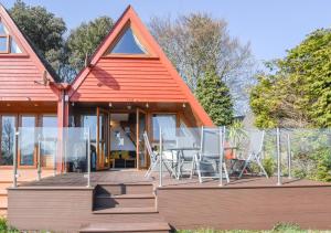 a house with an orange roof and chairs on a deck at Chalet 124 in Deal