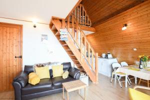 a living room with a leather couch and a staircase at Chalet 124 in Deal +14 photos