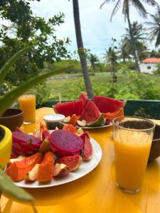 a table with plates of fruit and a glass of orange juice at Casa Bela Vida in Fortim