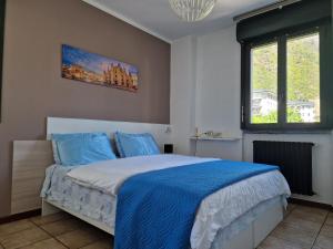 a bedroom with a bed with blue sheets and a window at Bernina Station Suite - 30 Steps to the Red Train in Tirano