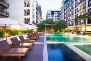a hotel swimming pool with lounge chairs and umbrellas at Amanta Hotel & Residence Ratchada in Bangkok