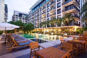 un patio del hotel con mesas y sillas y una piscina en Amanta Hotel & Residence Ratchada en Bangkok