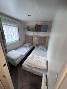 a small room with two beds and a window at mh44 au calme 6 personnes Bois Dormant 4 étoiles in Saint-Jean-de-Monts