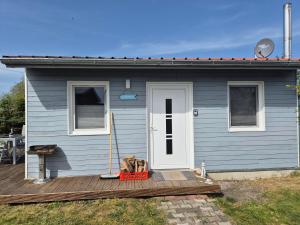 un cane seduto sul portico di una casa blu di Ferienwohnung am Stettiner Haff a Mönkebude Altre 4 foto