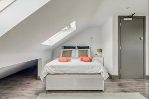 Dormitorio blanco con cama con almohadas de color naranja en The Little Oaks, en Birmingham