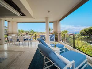 a room with a balcony with blue chairs and tables at Beautiful Azure Azul M212 At Luxuriousbreathtaking Wailea Beach Villas! in Wailea