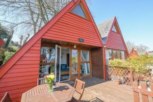 een rood huis met een tafel en stoelen op een terras bij Chalet Fortyfive in Deal