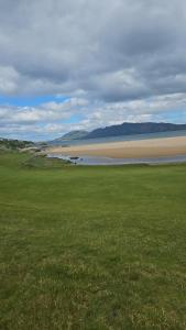 a green field with a beach and a body of water at Dungloe House in Dungloe