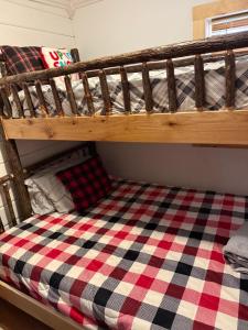 a bunk bed with a checkered blanket on it at The Cabins at Walnut Grove-minutes from Hunter and Windham in Ashland