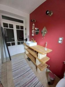 a bathroom with a sink and a red wall at Maison chaleureuse in Saint-Quentin-la-Poterie
