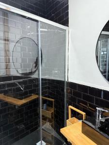a glass shower in a bathroom with black tiles at Villa Maréa in Algeciras