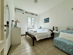 a white bedroom with a bed and a chair at Terrace & Parking - Holiday Home near Fegina Beach in Monterosso al Mare