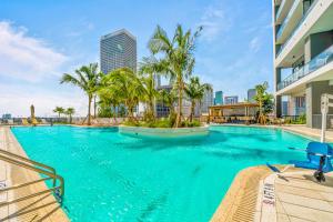 a large swimming pool with palm trees in a city at Ultimate Elegance Studio with Panoramic City Views in Miami