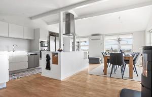 una cucina e una sala da pranzo con armadi bianchi e tavolo di 4 Bedroom Stunning Home In Hjørring a Hjørring