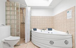 un bagno con una vasca bianca e un water di 4 Bedroom Stunning Home In Hjørring a Hjørring